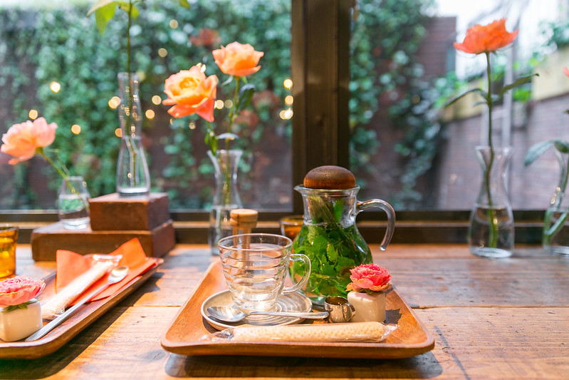 Chá de Hortelã em um bule de vidro sob uma bandeja de madeira em uma mesa de café decorada com rosas