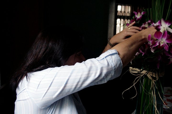 Mulher adulta em roupas sociais arrumando suas orquídeas