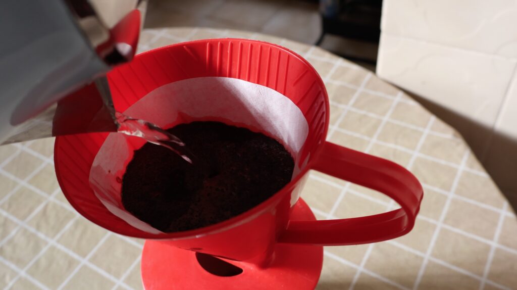 Água sendo adicionada em um filtro de café da cor vermelha