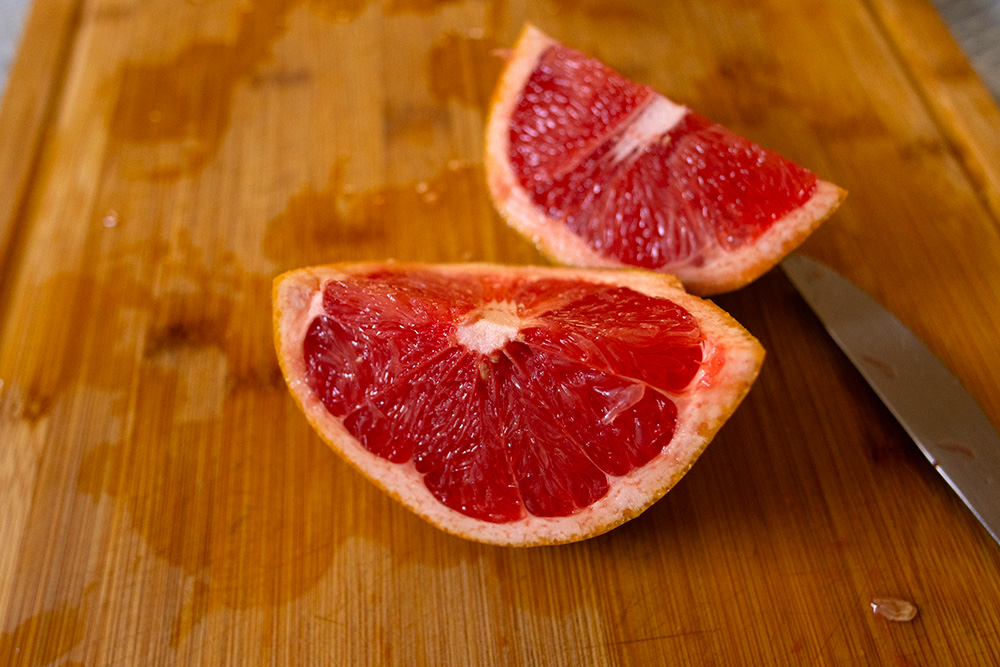 toranja ou grapefruit partida ao meio em uma tábua de madeira