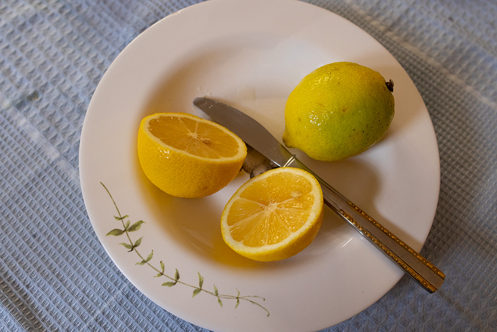 Limão Siciliano amarelo partido ao meio com uma faca em um prato branco