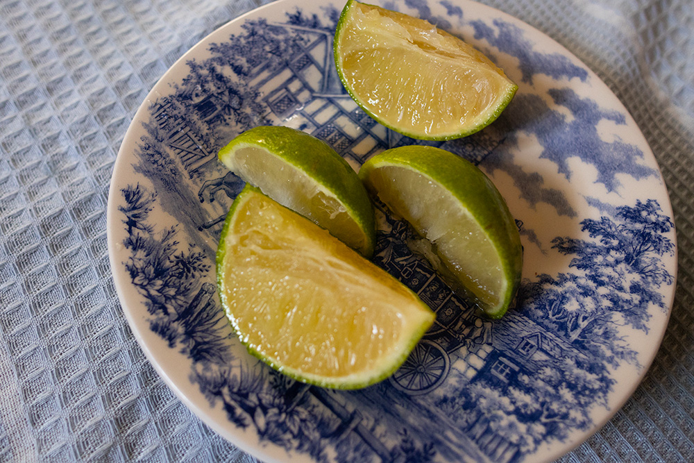 limão verde partido em 4 partes em um vaso com estampa azul