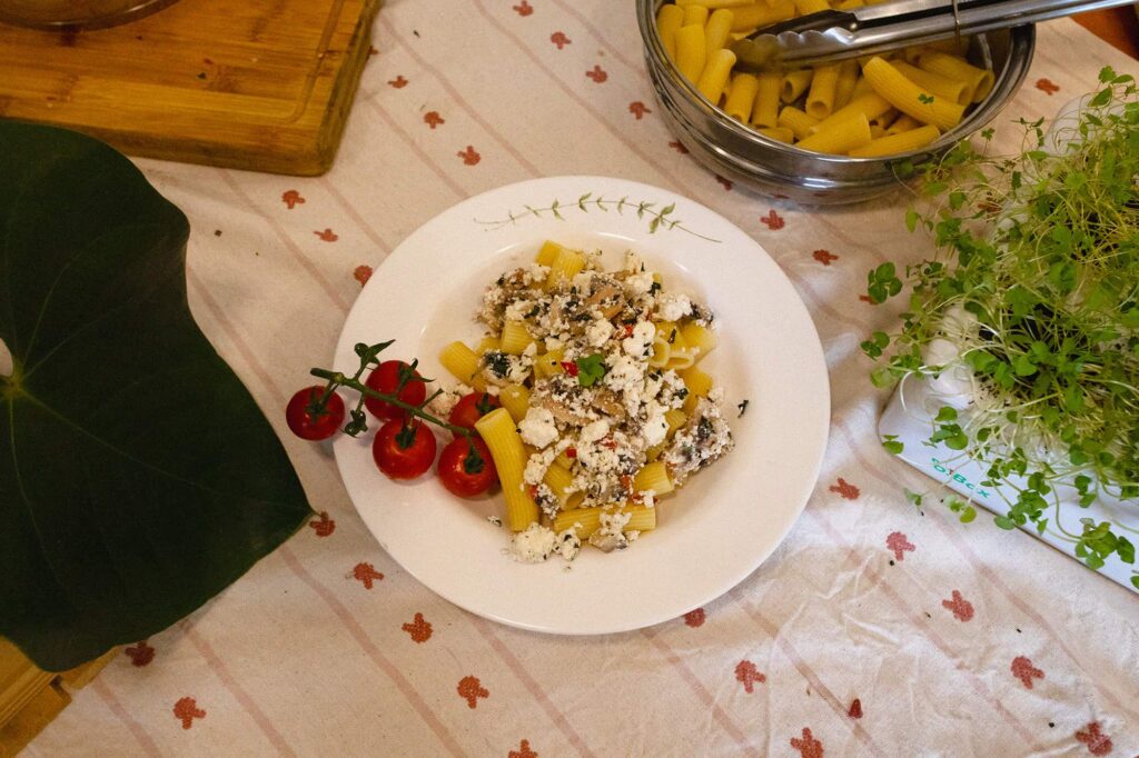 Prato de macarrão com tomates cereja e molho de ricota com cogumelos ao lado de uma B Box Horta Inteligente da Brota Company